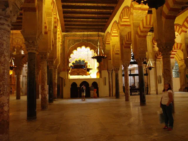De zuilenzaal van de Mezquita-Catedral in Córdoba, met rijen zuilen en dubbele hoefijzerbogen in rood en wit, en achterin de mihrab De zuilenzaal van de Mezquita-Catedral in Córdoba, met rijen zuilen en dubbele hoefijzerbogen in rood en wit, en achterin de mihrab