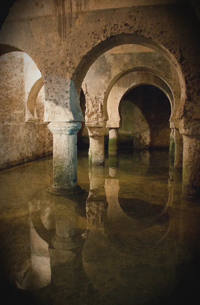 De Moorse cisterne (aljibe árabe) onder de Casa de las Veletas in Cáceres met hoefijzerbogen boven het water