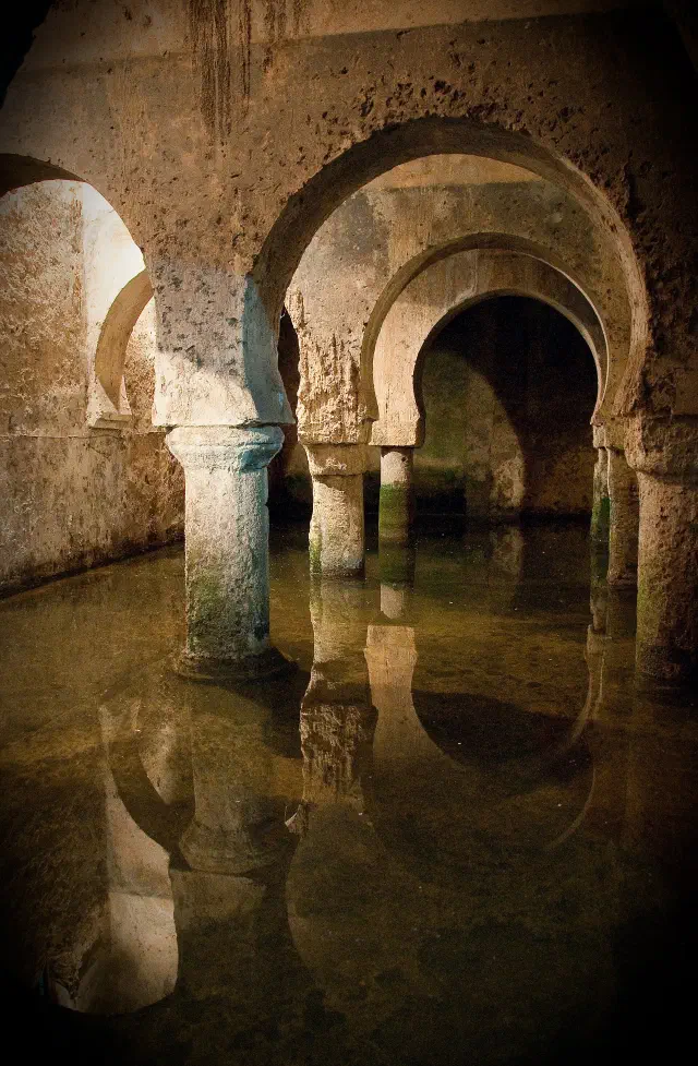 De Moorse cisterne (aljibe árabe) onder de Casa de las Veletas in Cáceres met hoefijzerbogen boven het water
