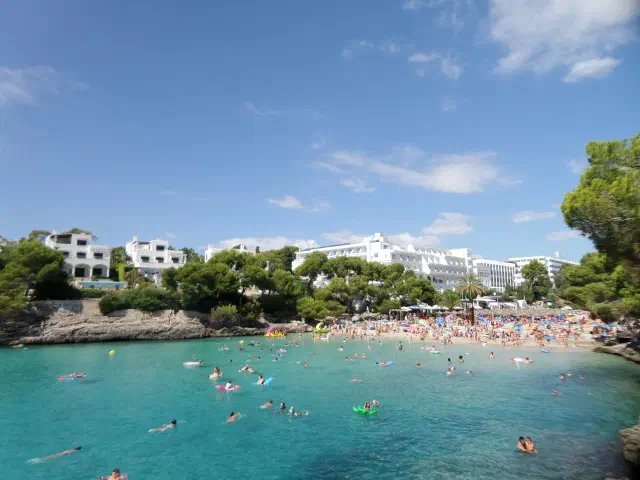 Het zandstrand van Cala Gran in Cala d'Or met helder water en pijnbomen op de rotsen Het zandstrand van Cala Gran in Cala d'Or met helder water en pijnbomen op de rotsen