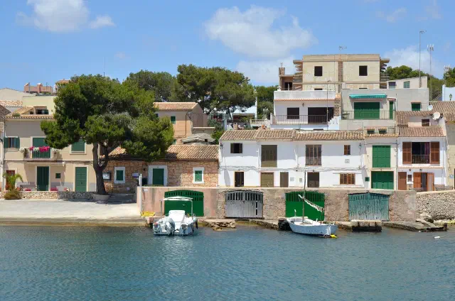 De natuurlijke haven van Portopetro met vissersboten en witte huizen aan het water De natuurlijke haven van Portopetro met vissersboten en witte huizen aan het water