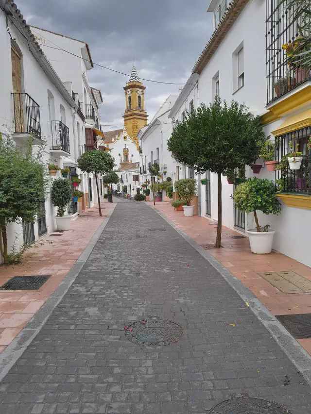 Witgekalkte straat in de Casco Antiguo van Estepona met de klokkentoren van Nuestra Señora de los Remedios op de achtergrond