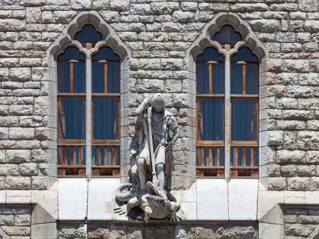 Het stenen beeld van de heilige Joris die de draak verslaat boven de ingang van Casa Botines in León Het stenen beeld van de heilige Joris die de draak verslaat boven de ingang van Casa Botines in León