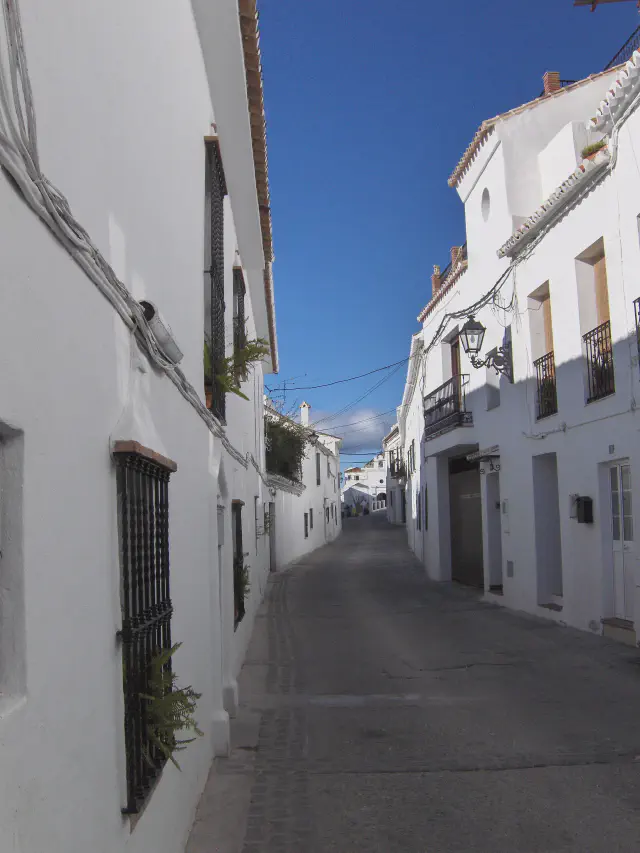 Een witgekalkte straat in het Casco Antiguo van Mijas Pueblo met smeedijzeren balkons