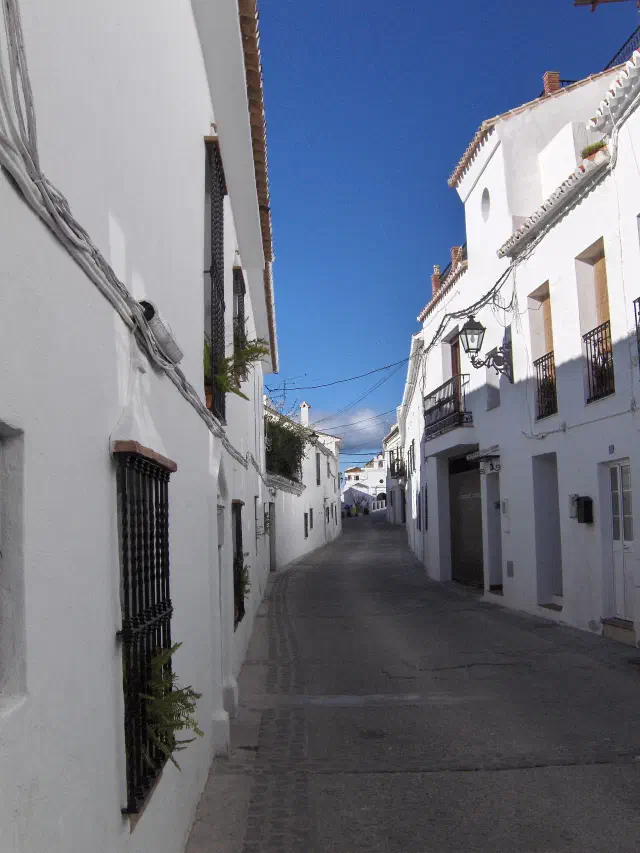 Een witgekalkte straat in het Casco Antiguo van Mijas Pueblo met smeedijzeren balkons