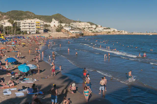 Het populaire strand Platja de Sant Sebastia in Sitges met goudkleurig zand en de kerk op de achtergrond Het populaire strand Platja de Sant Sebastia in Sitges met goudkleurig zand en de kerk op de achtergrond