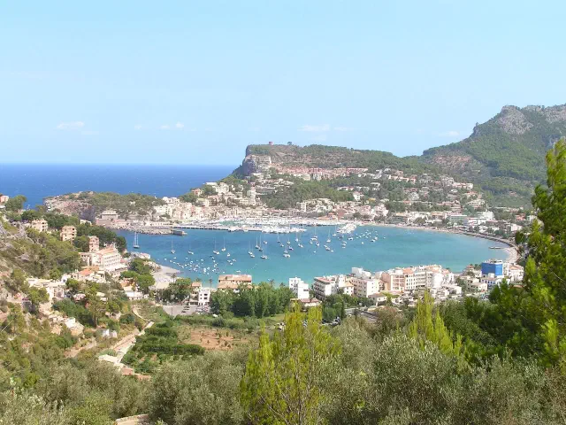 De hoefijzervormige natuurlijke haven van Port de Sóller met boten, witte huizen en de bergen op de achtergrond De hoefijzervormige natuurlijke haven van Port de Sóller met boten, witte huizen en de bergen op de achtergrond